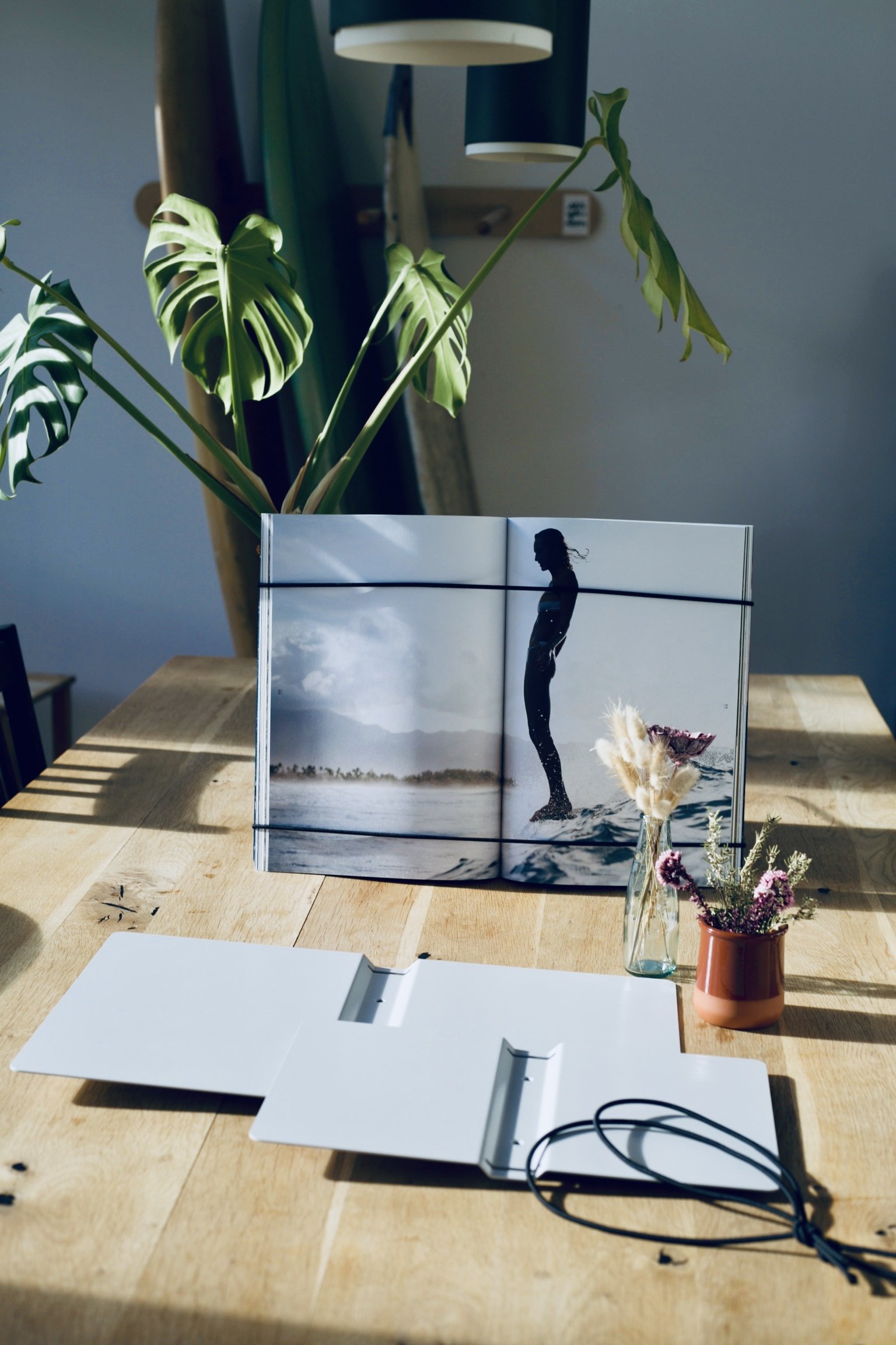 FOCUS | FRAME mit aufgeschlagenem Coffee Table Book auf dem Tisch, davor ein geöffneter Rahmen in Lichtgrau