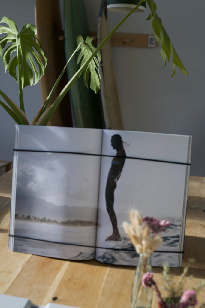 Aufgeschlagenes Coffee Table Book in FOCUS | FRAME auf einem Holztisch mit Pflanzen